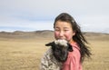 Young mongolian girl carrying a baby sheep in a steppe