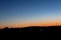 A young moon on an orange-blue sunset sky over a dark forest. Horizontal orientation. High quality photo Royalty Free Stock Photo