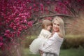 Young mother with adorable daughter in park with blossom tree. Happy mother and child.