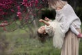 Young mother with adorable daughter in park with blossom tree. Happy mother and child.