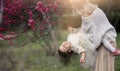 Young mother with adorable daughter in park with blossom tree. Happy mother and child.