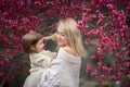 Young mother with adorable daughter in park with blossom tree. Happy mother and child.