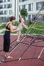 Mother Supports Toddler on Rope Climbing Frame. Family concept Royalty Free Stock Photo