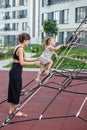 Mother Supports Toddler on Rope Climbing Frame. Family concept Royalty Free Stock Photo