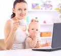 Young mother with baby sitting in front of an open laptop. Royalty Free Stock Photo