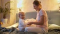 Young mother with baby son playing in bed and jumping. Family having time together, parenting, happy childhood and entertainment Royalty Free Stock Photo