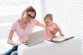 Young mother with baby working and using laptop.