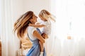 Young mother or babysitter with a little girl in her arms spin in the middle of the room