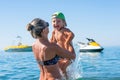 Young mother in black sunglasses and smiling baby boy son in green baseball cap playing in the sea in the day time. Positive human Royalty Free Stock Photo