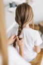 Young mother braids her little daughter`s hair, close-up