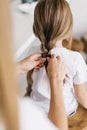 Young mother braids her little daughter`s hair, close-up