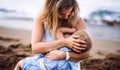 Young mother breasfeeding toddler daughter on beach on summer holiday. Royalty Free Stock Photo