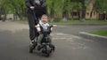 A young mother carries a small child on a tricycle. Two-year-old boy on a bicycle close-up. Royalty Free Stock Photo
