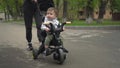 A young mother carries a small child on a tricycle. Two-year-old boy on a bicycle close-up. Royalty Free Stock Photo