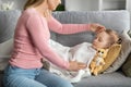 Young mother checking temperature of sick sleeping daughter lying on couch Royalty Free Stock Photo