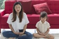 Young mother and child daughter doing yoga exercise sit on floor at home.