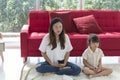 Young mother and child daughter doing yoga exercise sit on floor at home.