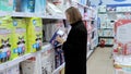 A young mother chooses diapers in a supermarket in a mall. Hygiene products for children. Russia, Tomsk 10.08.2022 Royalty Free Stock Photo