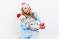 A young mother, on Christmas day gives a gift to a newborn child, a girl holds a baby in her arms in a Christmas hat Royalty Free Stock Photo