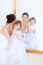 Young mother and curly daughter in front of mirror