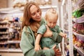 Young mother with cute baby in her hands walks around supermarket. Beautiful mom and little blonde daughter in similar Royalty Free Stock Photo