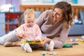 Young mother and cute baby playing on floor at home. Mom teaching her little girl how to play on toy metallophone Royalty Free Stock Photo