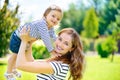 Young mother and cute daughter with blue eyes playing at park