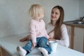 Young mother and cute little girl look at each other. Morning on kitchen Royalty Free Stock Photo