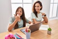 Young mother and daughter doing homework at home pointing thumb up to the side smiling happy with open mouth Royalty Free Stock Photo
