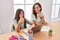 Young mother and daughter doing homework at home smiling happy and positive, thumb up doing excellent and approval sign Royalty Free Stock Photo