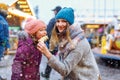 Young mother and daughter eating white chocolate covered fruits on skewer on traditional German Christmas market. Happy Royalty Free Stock Photo