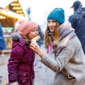 Young mother and daughter eating white chocolate covered fruits on skewer on traditional German Christmas market. Happy Royalty Free Stock Photo