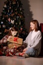 young mother and daughter open Christmas Lighting Present Gift Box front of Xmas Tree. Happy Mom with kid girl in Magic Royalty Free Stock Photo