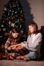 young mother and daughter open Christmas Lighting Present Gift Box front of Xmas Tree. Happy Mom with kid girl in Magic Royalty Free Stock Photo