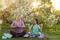 a young mother and daughter perform yoga exercises in the park on a gym mat. healthy lifestyle.