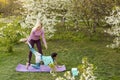 a young mother and daughter perform yoga exercises in the park on a gym mat. healthy lifestyle.