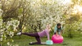 a young mother and daughter perform yoga exercises in the park on a gym mat. healthy lifestyle.