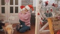 Young mother and daughter in pink pullovers and red hat hugging at Christmas