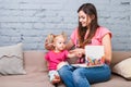 Young mother and daughter of two years old blonde use laptop computer laptop white with bright print sitting on couch indoors Royalty Free Stock Photo