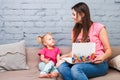 Young mother and daughter of two years old blonde use laptop computer laptop white with bright print sitting on couch indoors Royalty Free Stock Photo