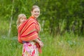 Young mother with daughter in wrap walking