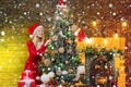 Girl in snow. Young Mother decorate the Christmas tree indoors. Woman decorating Christmas tree with ball or bauble Royalty Free Stock Photo