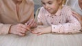 Young mother doing manicure for daughter, spending time together, female leisure