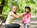 Young mother dresses her daughter's bicycle helmet Royalty Free Stock Photo