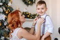 Young mother dresses his son a bow tie on the background of Christmas decorations Royalty Free Stock Photo