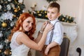 Young mother dresses his son a bow tie on the background of Christmas decorations Royalty Free Stock Photo