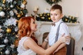 Young mother dresses his son a bow tie on the background of Christmas decorations Royalty Free Stock Photo