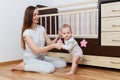 A young mother and an eight-month-old child play at home near the crib Royalty Free Stock Photo