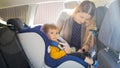 Portrait of young mother fastening belts and bucle of car children safety seat Royalty Free Stock Photo