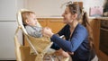 Young mother fastening seat belts on baby feeding highchair before giving food to her son. Concept of parenting, healthy nutrition Royalty Free Stock Photo